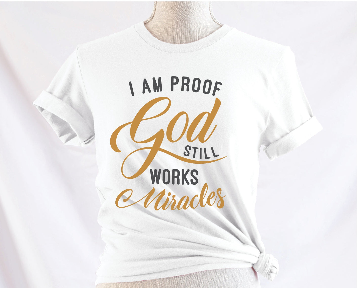 I am proof God still works miracles Christian aesthetic testimony design printed in charcoal and gold on white unisex t-shirt for women