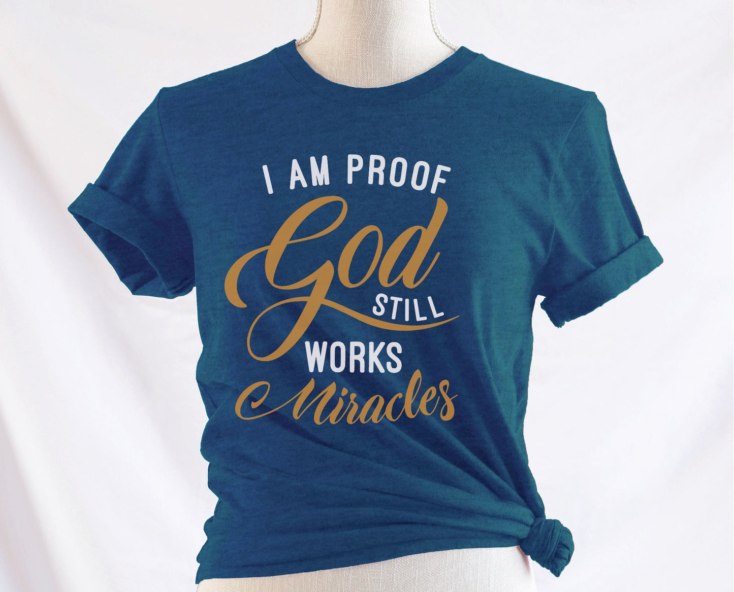 I am proof God still works miracles Christian aesthetic testimony design printed in white and gold on soft heather deep teal unisex t-shirt for women
