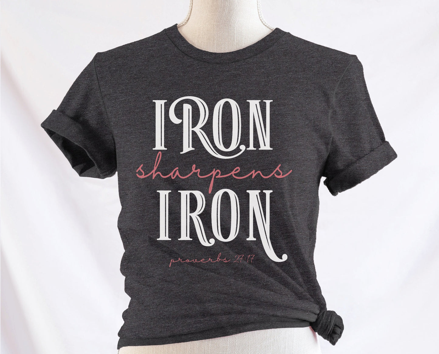 Iron Sharpens Iron Proverbs 27:17 Christian aesthetic design printed in white and mauve on soft heather dark gray unisex t-shirt for women's groups