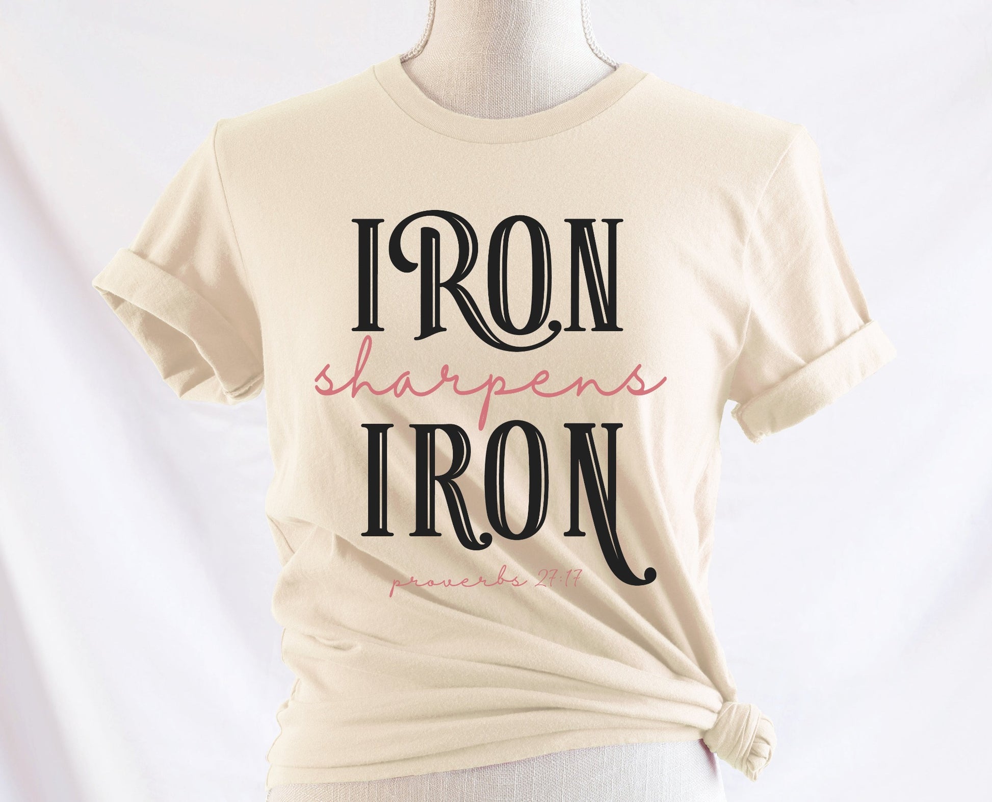 Iron Sharpens Iron Proverbs 27:17 Christian aesthetic design printed in black and mauve on ladies soft cream unisex t-shirt for women's groups