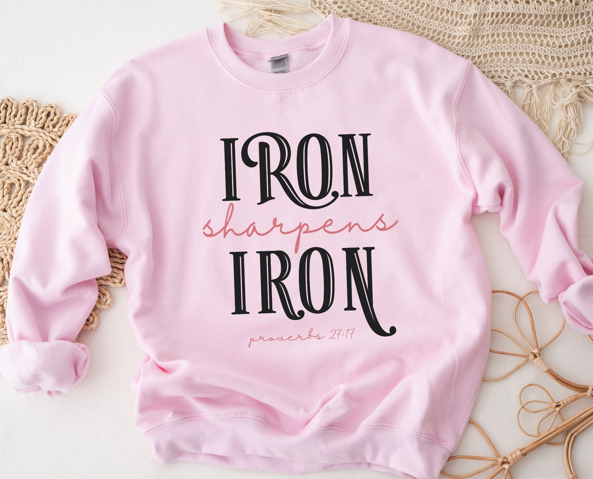 Iron Sharpens Iron Proverbs 27:17 Christian aesthetic design printed in black and mauve on cozy light pink unisex crewneck sweatshirt for women's groups