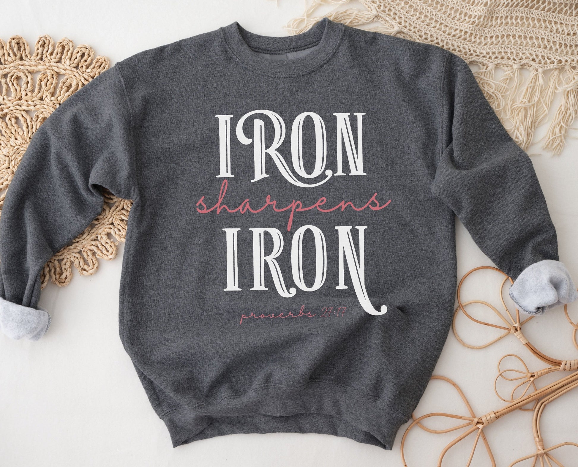 Iron Sharpens Iron Proverbs 27:17 Christian aesthetic design printed in white and mauve on cozy heather dark gray unisex crewneck sweatshirt for women's groups