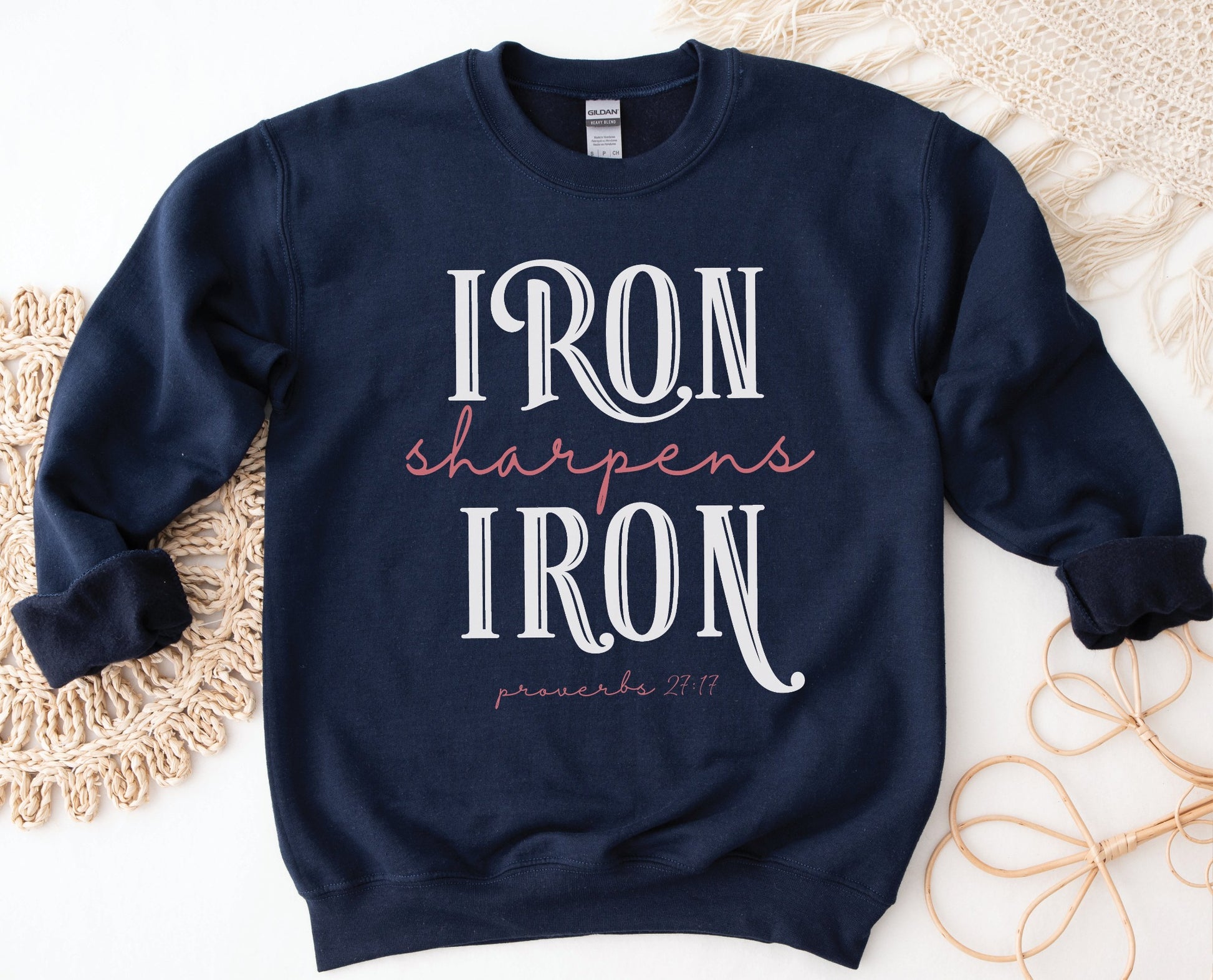 Iron Sharpens Iron Proverbs 27:17 Christian aesthetic design printed in white and mauve on cozy navy blue unisex crewneck sweatshirt for women's groups