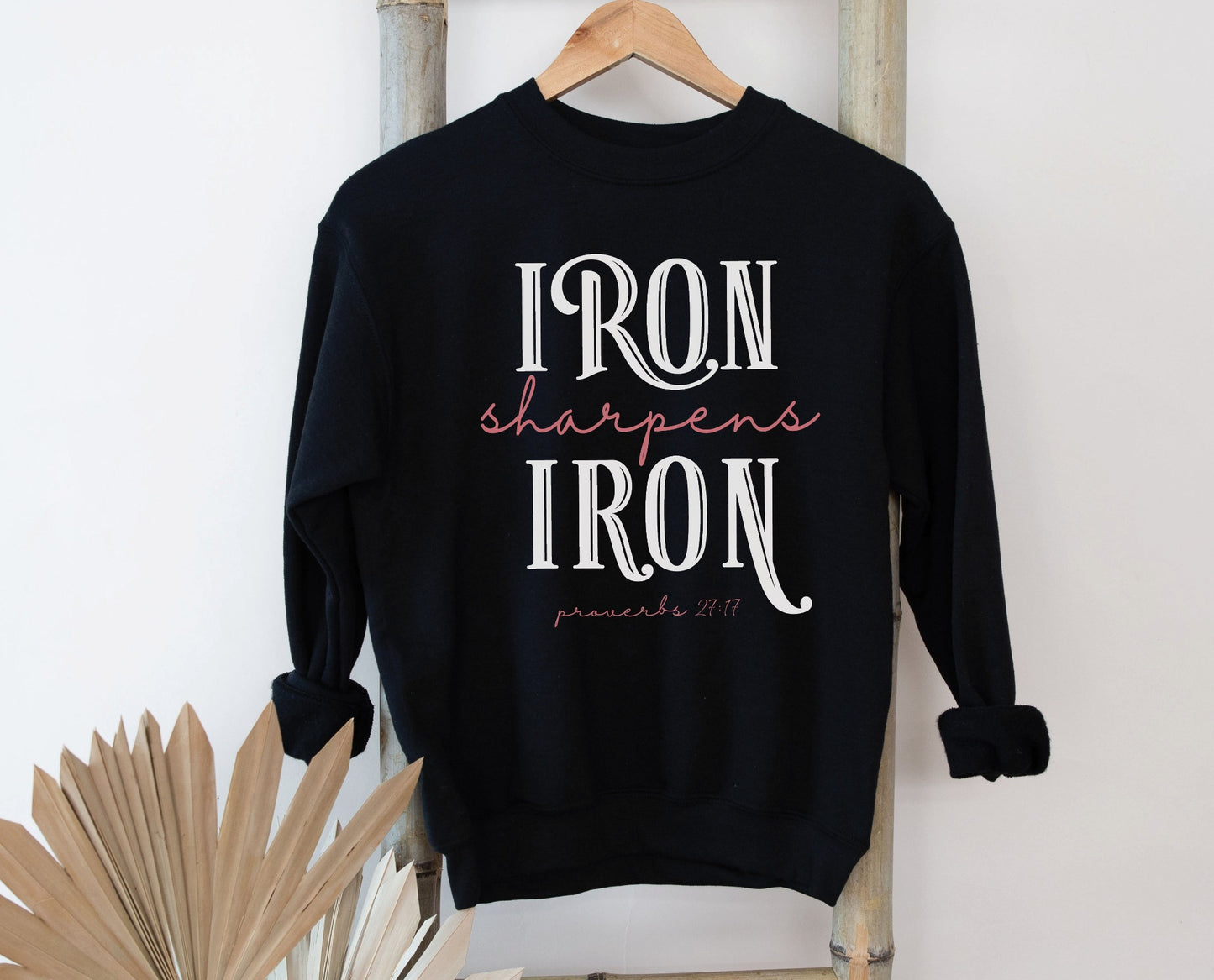Iron Sharpens Iron Proverbs 27:17 Christian aesthetic design printed in white and mauve on cozy black unisex crewneck sweatshirt for women's groups