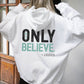 Young woman showing the back of a Do Not Be Afraid Only Believe Jesus Quote Mark 5:36 healing miracle bible verse Christian aesthetic textured black and teal printed on front and back of cozy white unisex hoodie sweatshirt