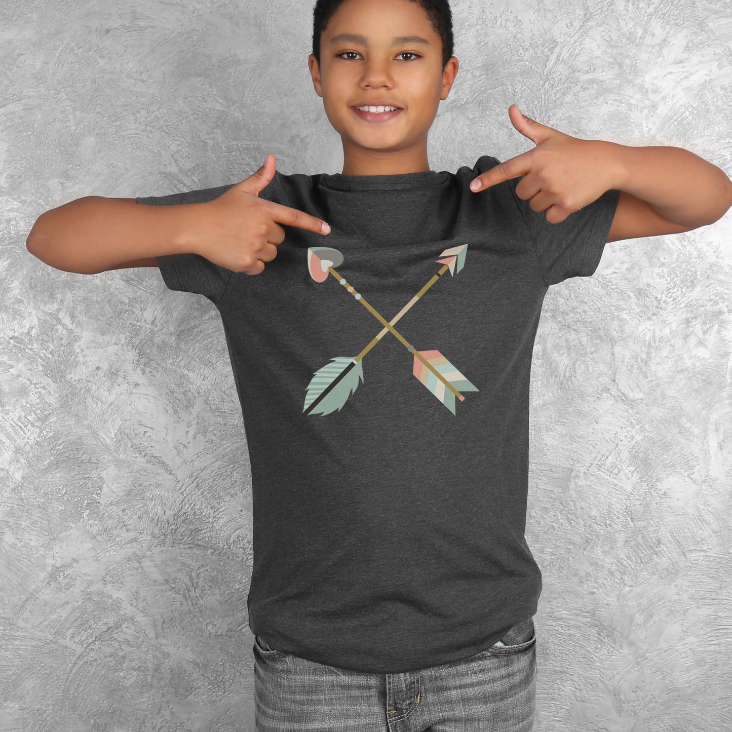 Teen boy wearing a matching mommy-and-me Youth size t-shirt in heather dark gray with teal blue and dusty pink pastel criss-cross boho arrows, one with a heart on the end, to match Christian homeschool mom's / women's "Raising Arrows" Psalm 127:4-5 bible verse t-shirt for boys and girls