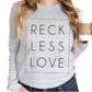 Woman holding Coffee wearing a Rectangle Reckless Love Christian aesthetic worship design printed in black on cozy white unisex long sleeve tee shirt for men and women