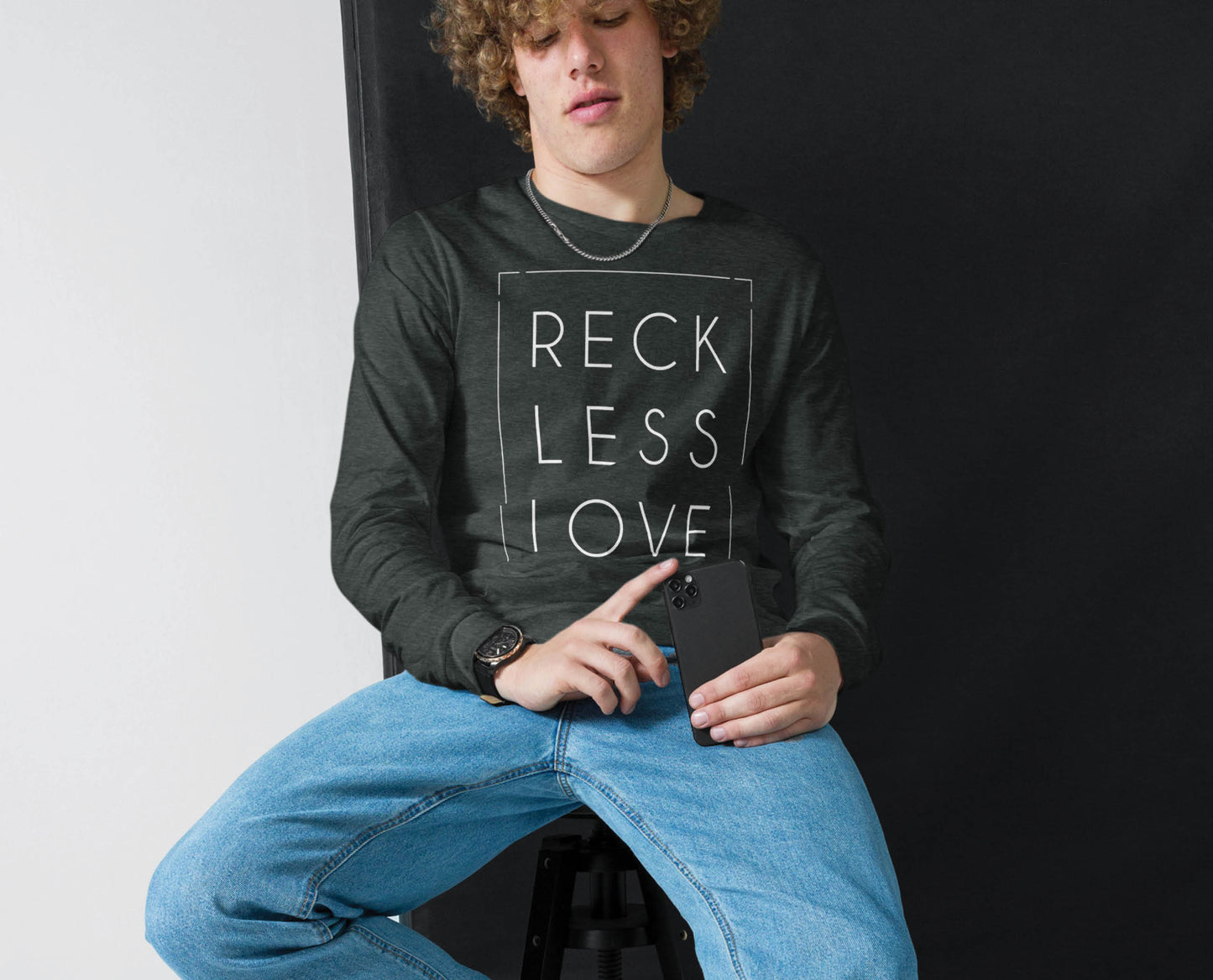 Young Man Teenage Boy wearing a Rectangle Reckless Love Christian aesthetic worship design printed in white on cozy heather dark gray unisex long sleeve tee shirt for men and women
