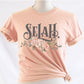 Selah Psalm bible verse watercolor floral Christian aesthetic design printed in charcoal gray, blush pink, sage green, on soft heather prism peach t-shirt for women